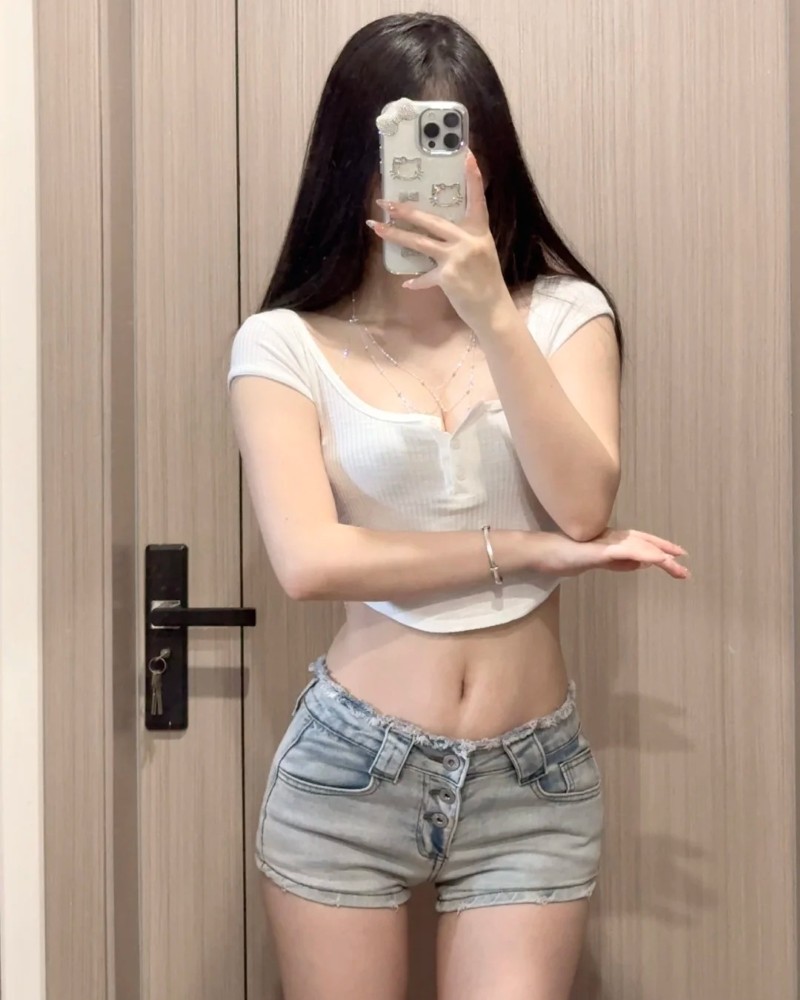 cô gái áo croptop trắng và quần short jean tạo dáng tự nhiên