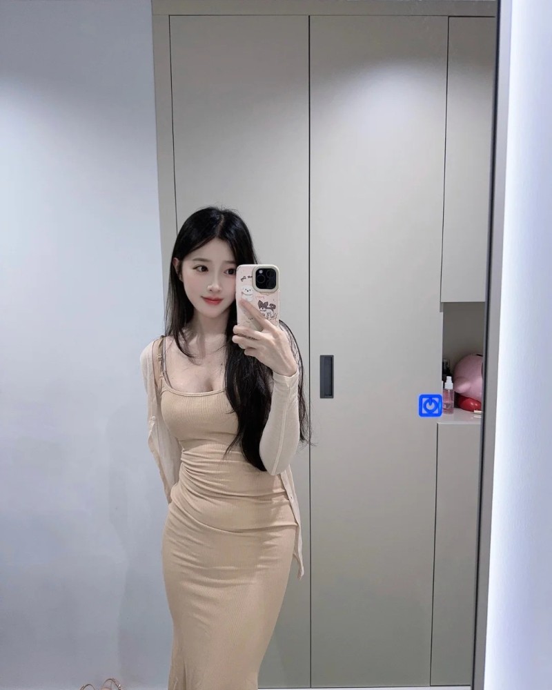 cô gái mặc váy be dài đứng bên hành lang sáng