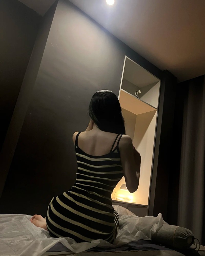 Cô gái ngồi quay lưng tạo dáng trong phòng