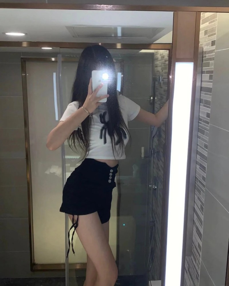 Cô gái mặc váy ngắn che mặt bằng điện thoại trong gương