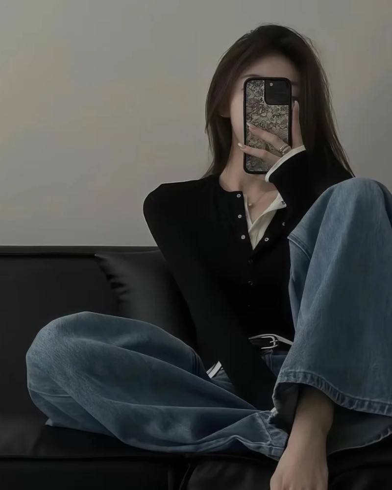 Cô gái ngồi khoanh chân dùng điện thoại che mặt