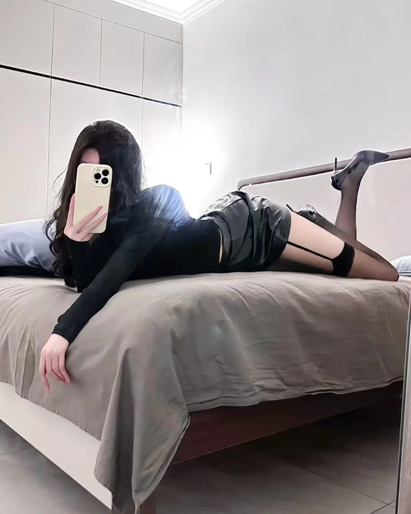 Cô gái chụp ảnh trên giường dùng điện thoại che mặt