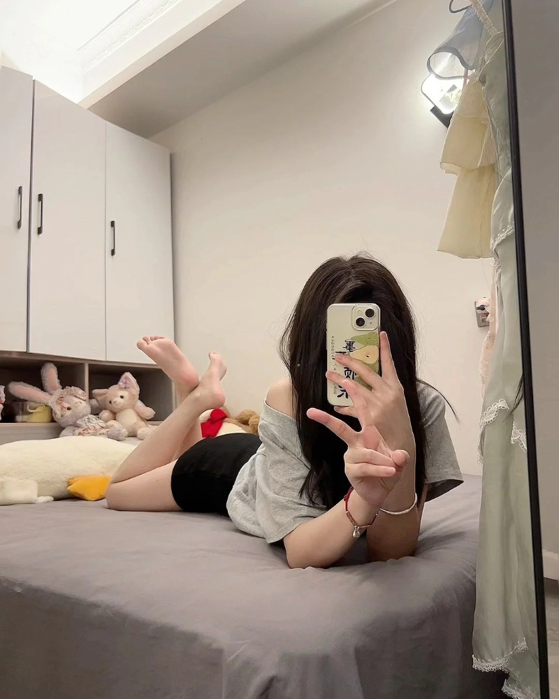 Cô gái nằm nghiêng dùng điện thoại che mặt khi chụp