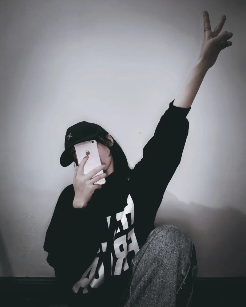 Cô gái mặc hoodie giơ tay che mặt bằng điện thoại