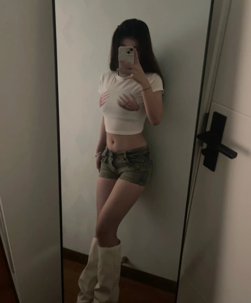 Cô gái đứng cạnh cửa dùng điện thoại che mặt