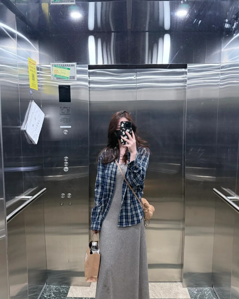 Cô gái đứng ngoài hành lang dùng điện thoại che mặt