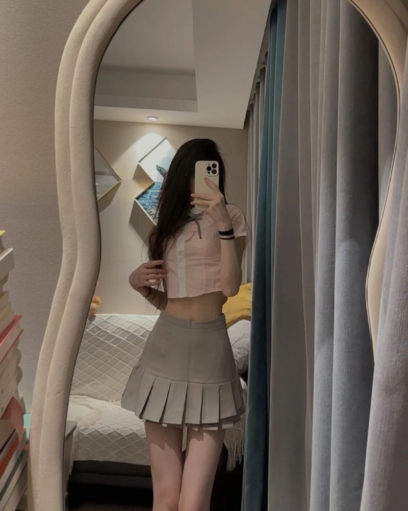 Cô gái tạo dáng trong phòng ngủ với điện thoại che mặt