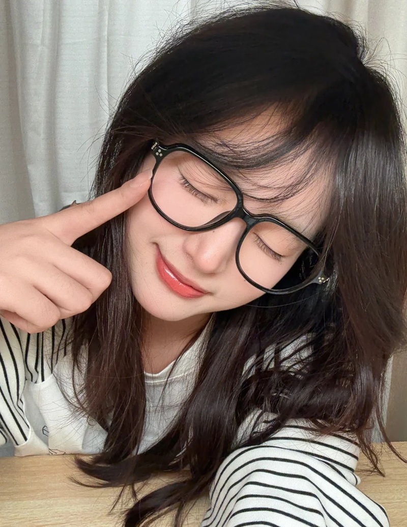Cô gái đeo kính ngồi trong quán với nụ cười tươi