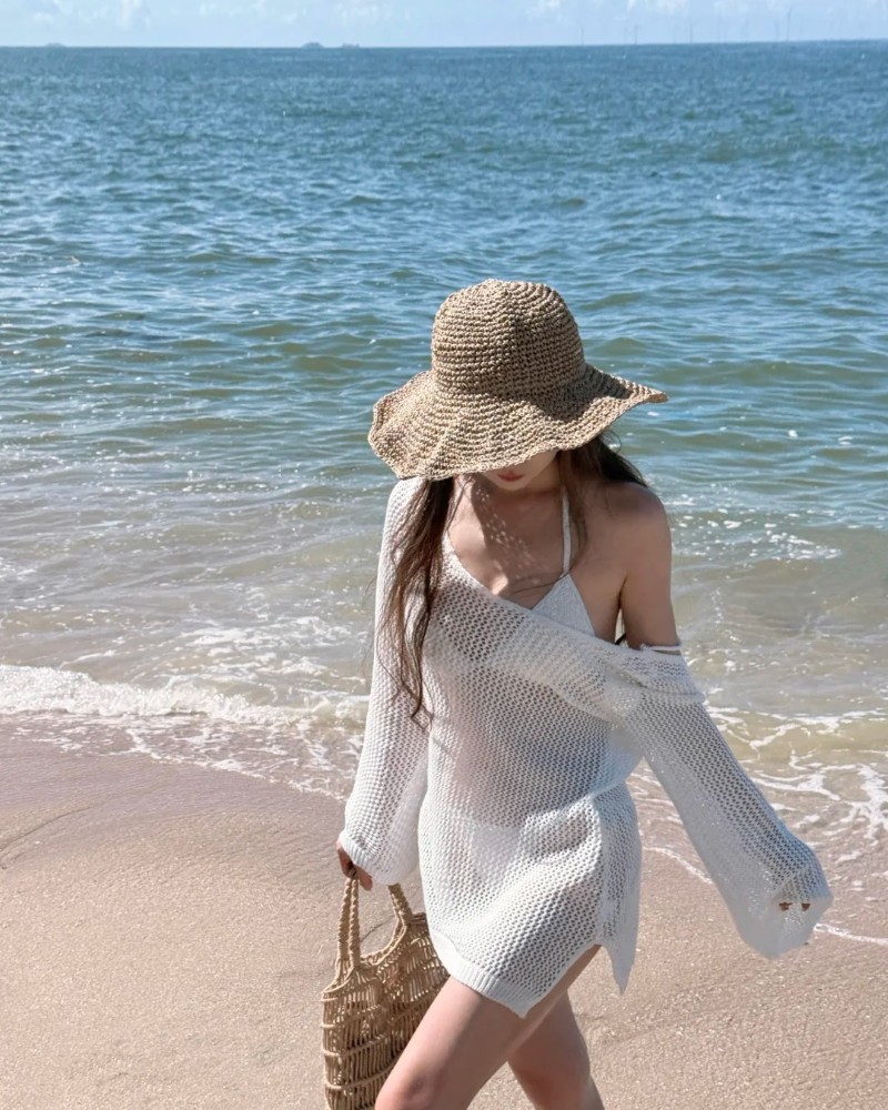 Cô gái đi dạo trên bãi biển đội mũ rộng vành