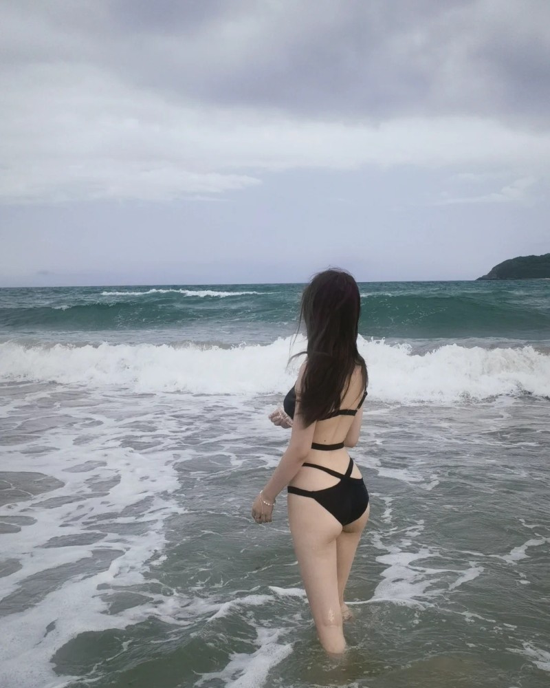 Cô gái bước đi trên bãi biển trong trang phục đen