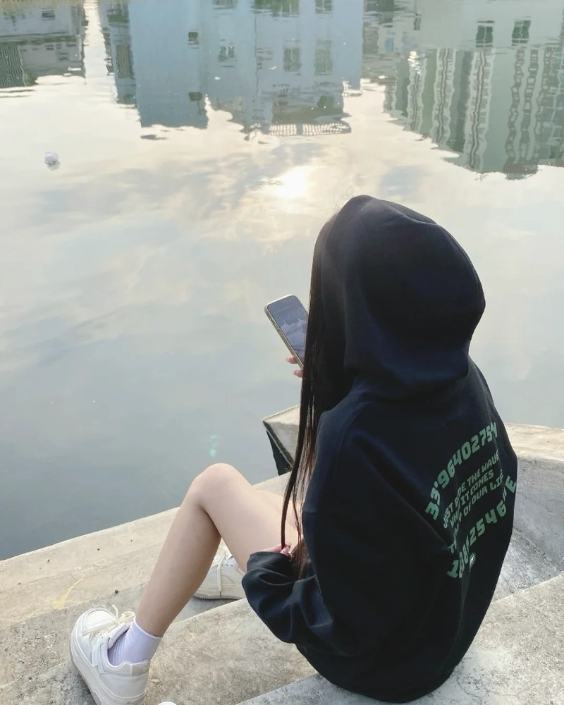 ảnh gái xinh ngầu đội mũ hoodie ngồi bên vỉa hè phong cách tối giản