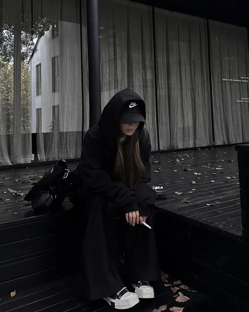 Cô gái đứng cạnh xe mô tô với outfit đen