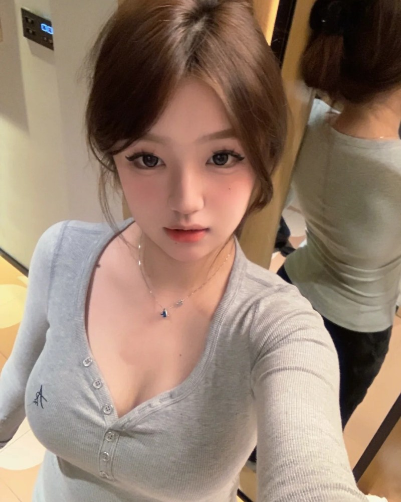 Cô gái ngồi gần bàn gỗ với áo len xám