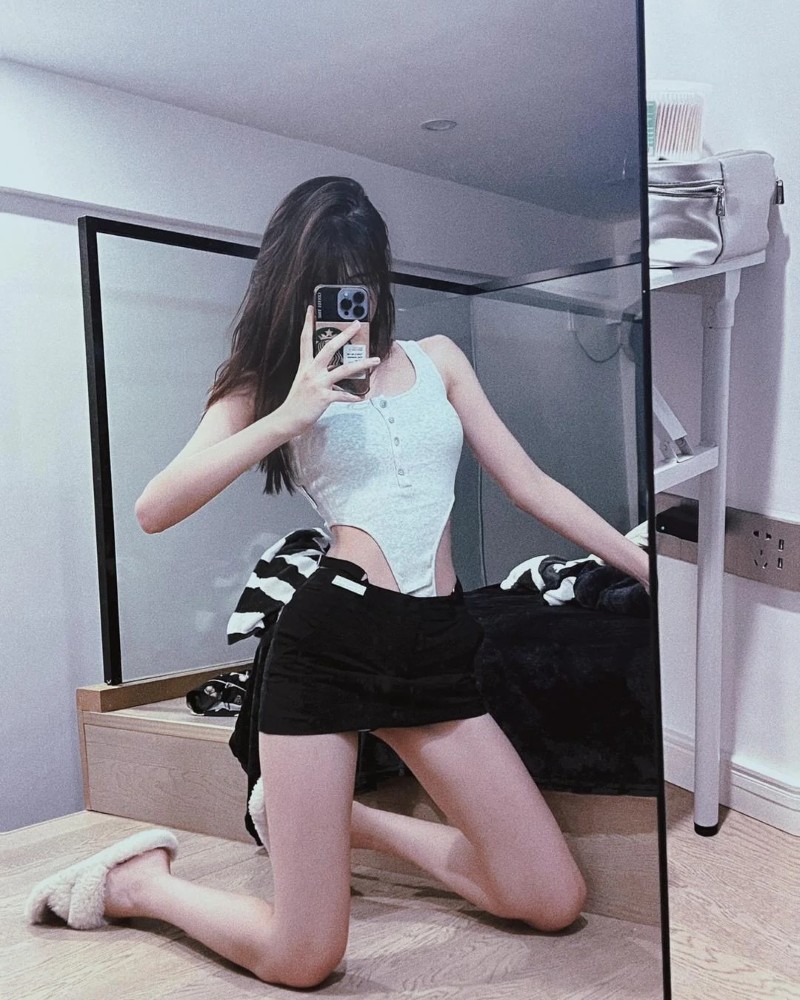 Cô gái mặc váy đen ngắn tạo dáng trong phòng