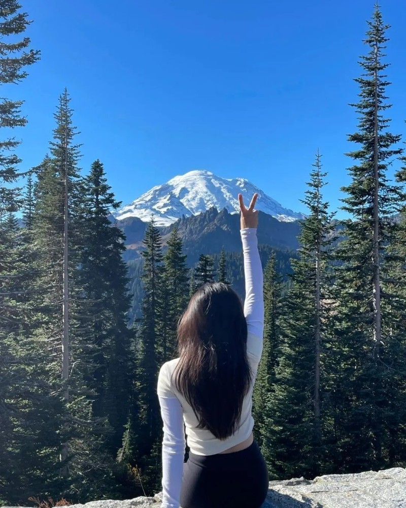 cô gái quay lưng chụp ảnh trước rừng núi