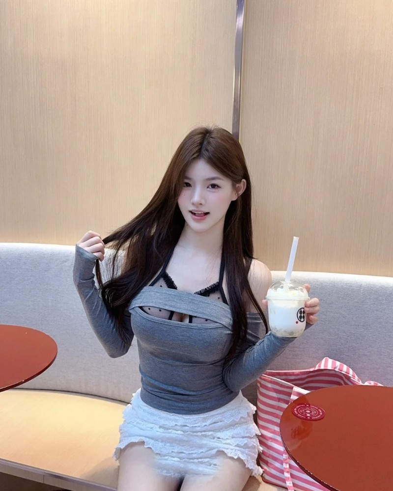 nàng mặc áo xám ngồi làm việc bên bàn gỗ