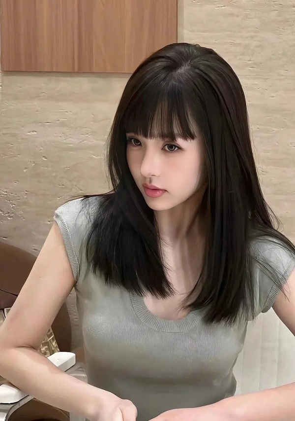 Cô gái tóc ngang vai diện áo thun xám ngồi trong quán