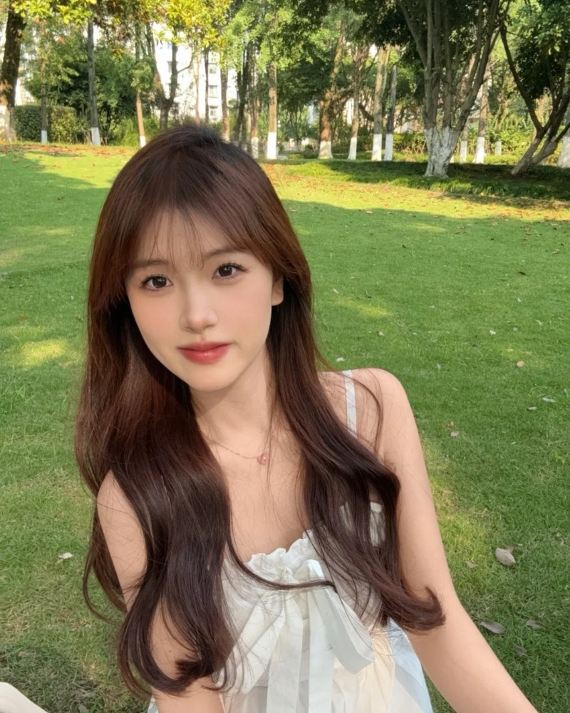 Cô gái tóc nâu tạo dáng trong khuôn viên xanh