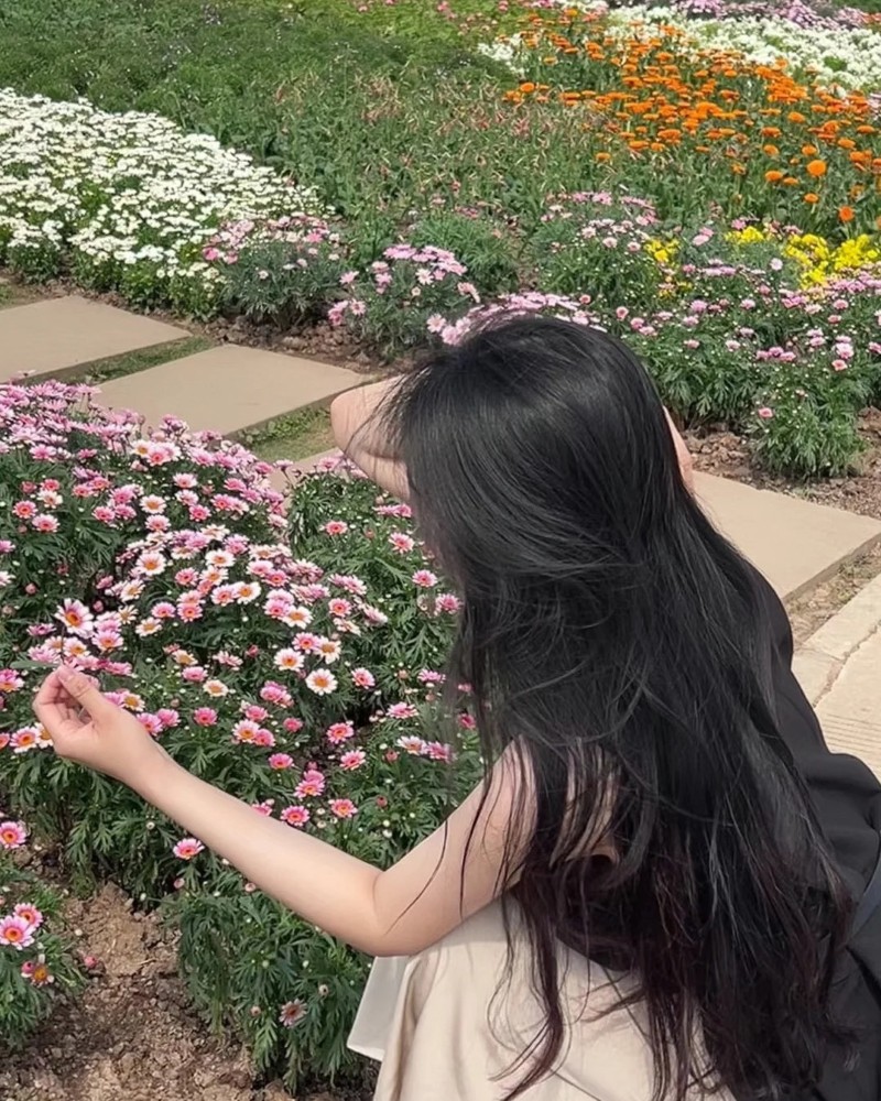 Cô gái ngồi giữa vườn hoa lớn với tóc dài thả