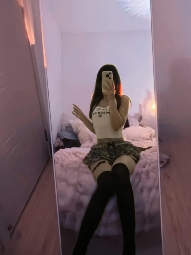 Cô gái ngồi trên giường selfie che mặt với điện thoại