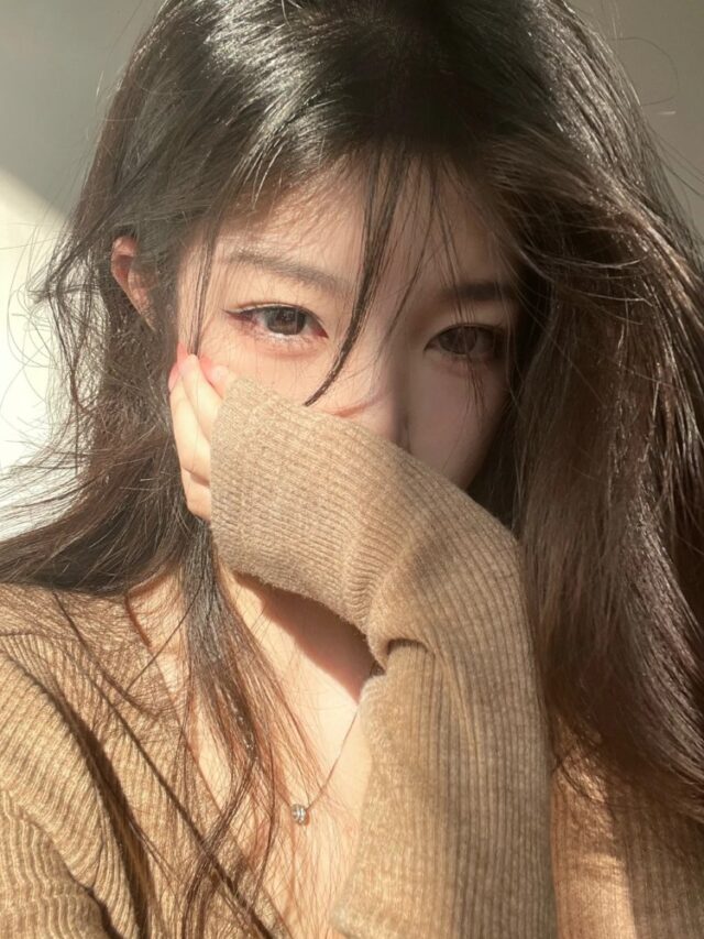 Cô gái che mặt bằng tay với ánh sáng vàng ấm