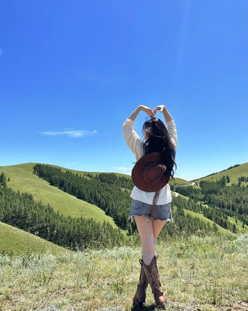 cô gái đứng trên đồi chụp hình dưới nắng