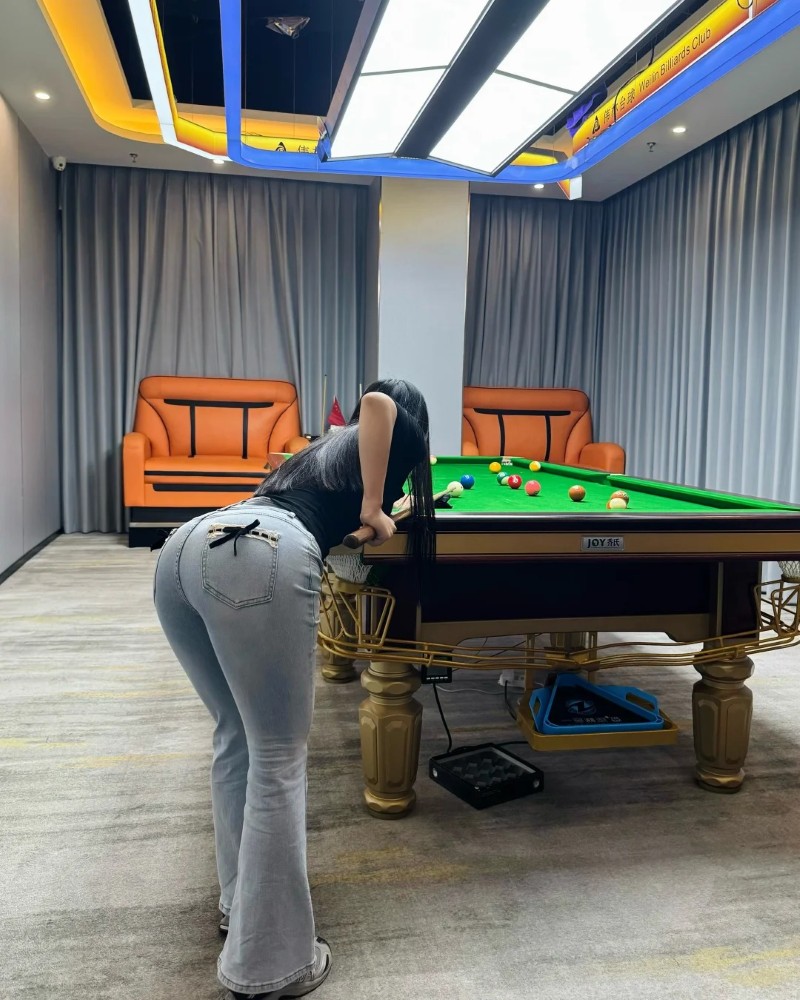 Người mẫu đứng cạnh bàn bida tạo dáng