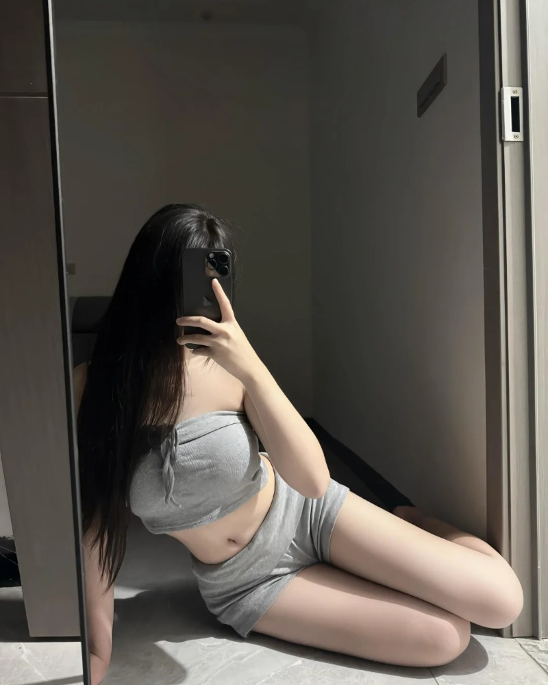 Nàng pose trên giường với áo len ôm sát