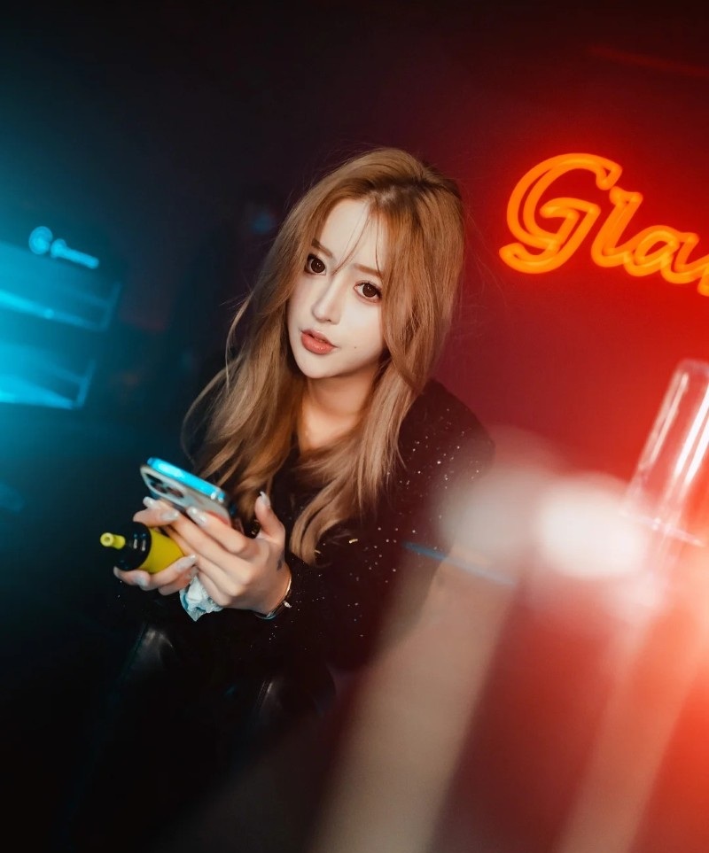 Cô gái quán bar tạo dáng trước biển hiệu neon