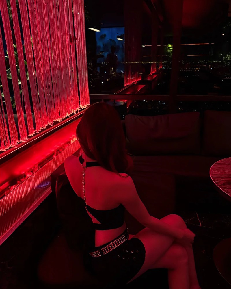 Người đẹp tạo dáng trong góc bar ánh sáng đỏ