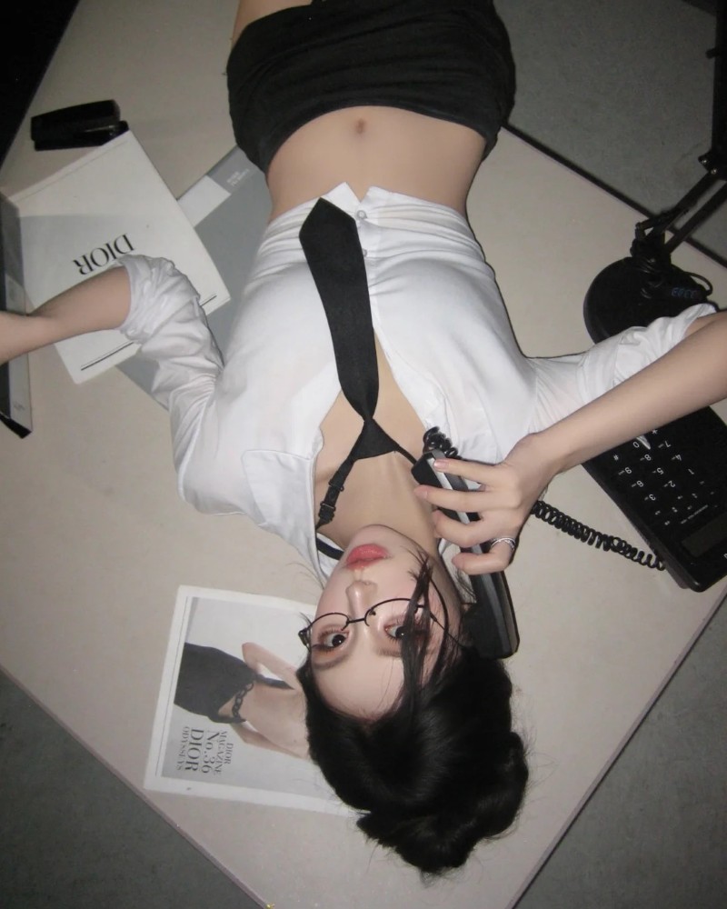 Cô gái mặc sơ mi trắng và váy công sở chụp ảnh trong phòng làm việc