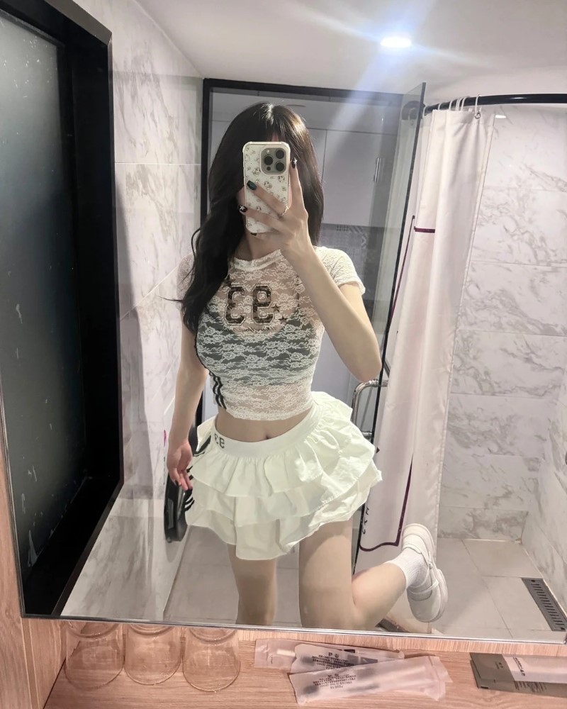 Người đẹp tạo dáng trước gương với outfit sáng màu