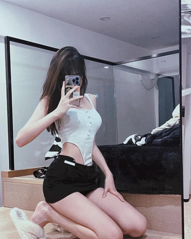 Nhân vật nữ tạo dáng trước gương trong váy ngắn