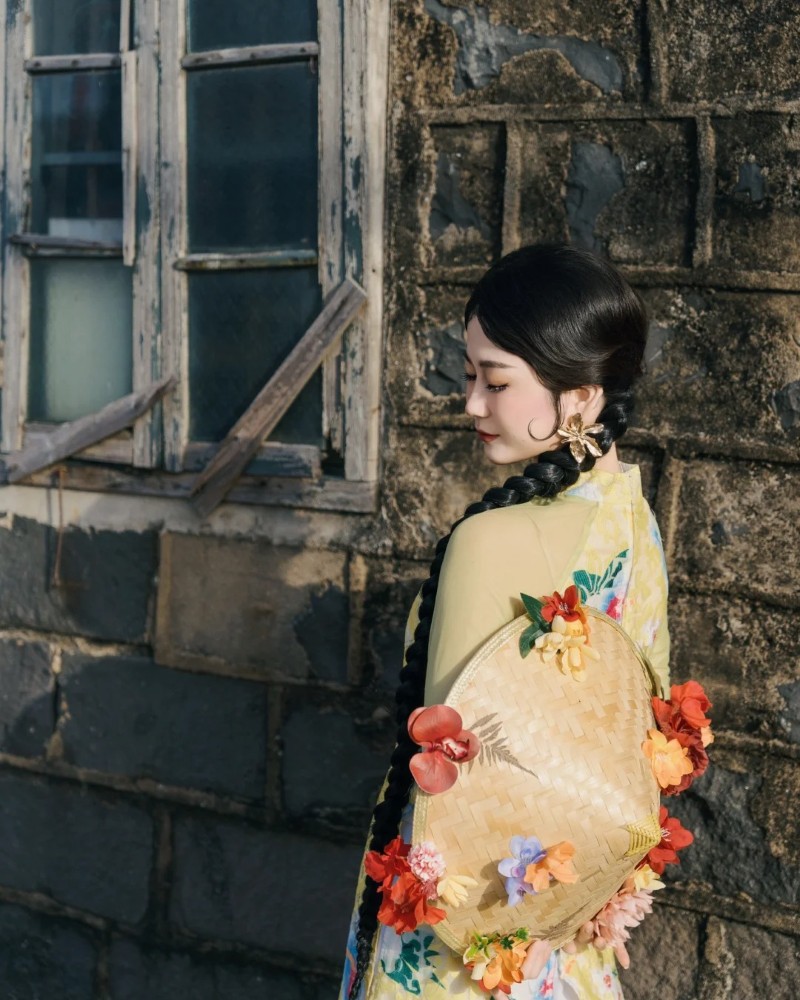 Người đẹp diện áo dài hoa đứng bên tường đá