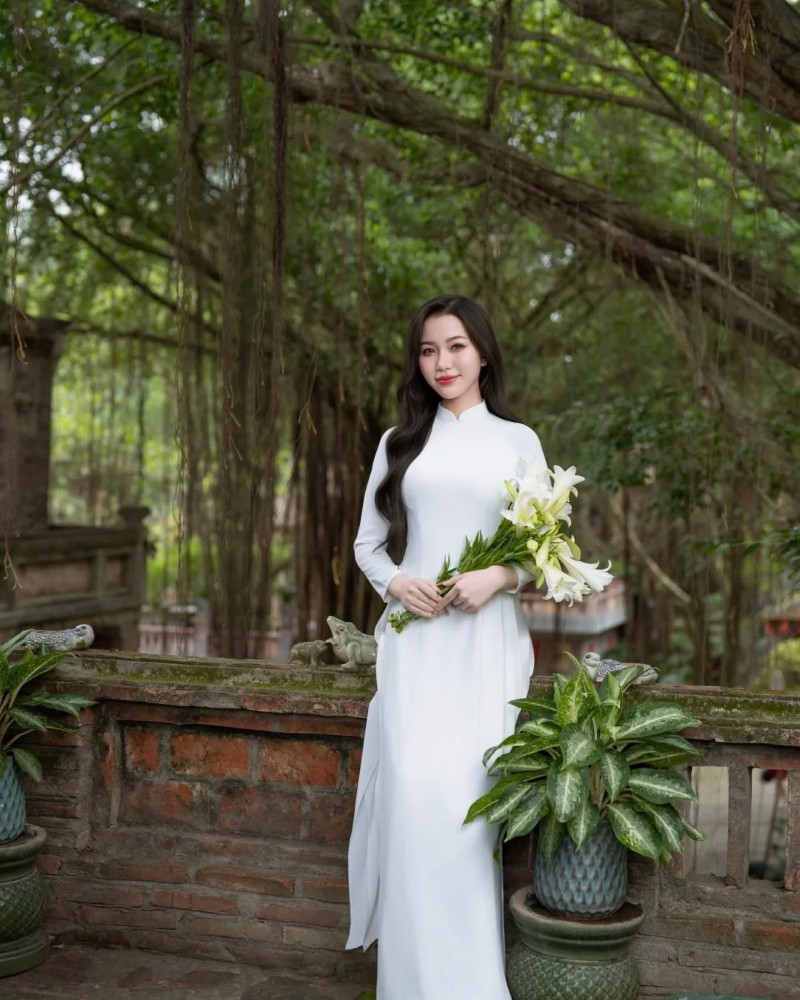 Nhân vật nữ diện áo dài xanh tạo dáng trong vườn