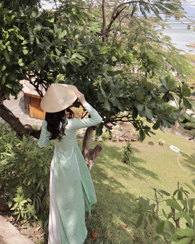 Người đẹp mặc áo dài chụp ảnh bên cây xanh