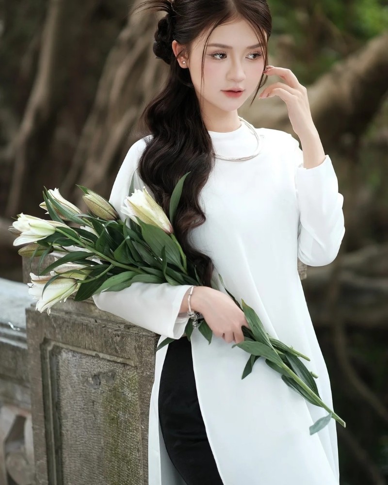 Cô gái mặc áo dài trắng cầm hoa nhẹ nhàng