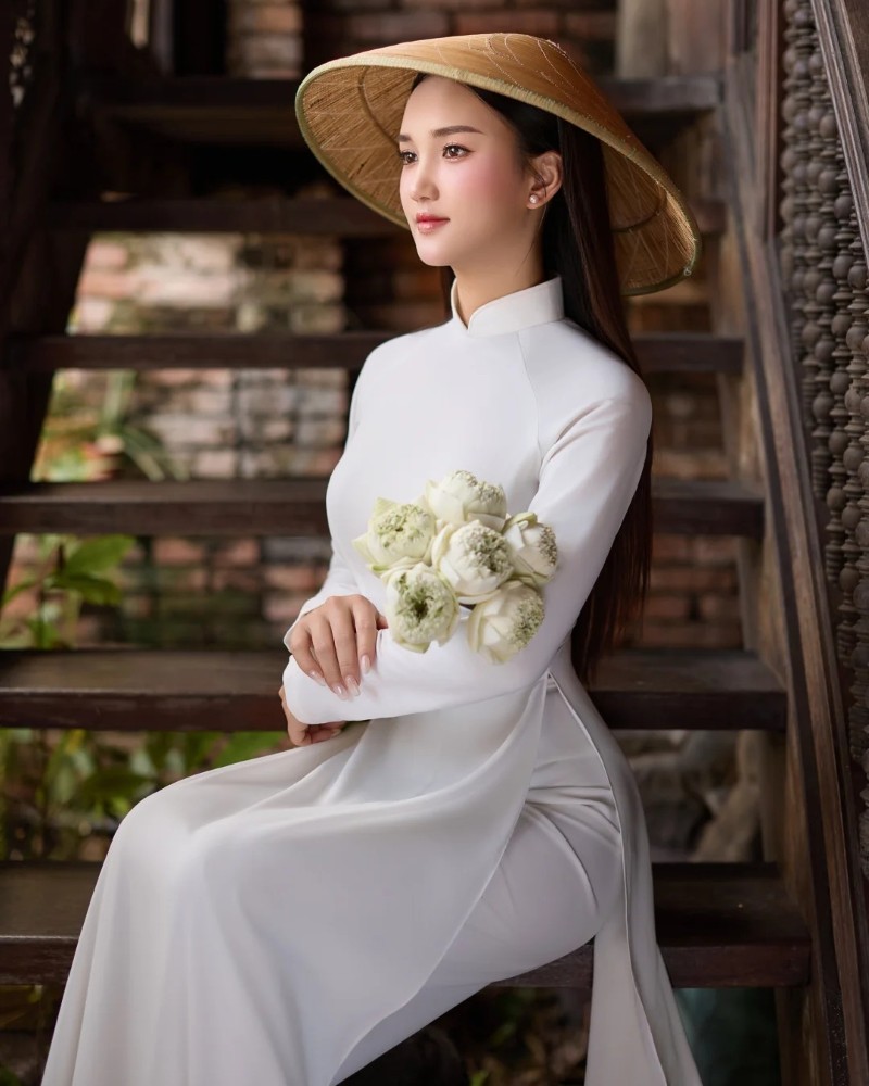 Nàng diện áo dài trắng cầm hoa đứng ngoài trời