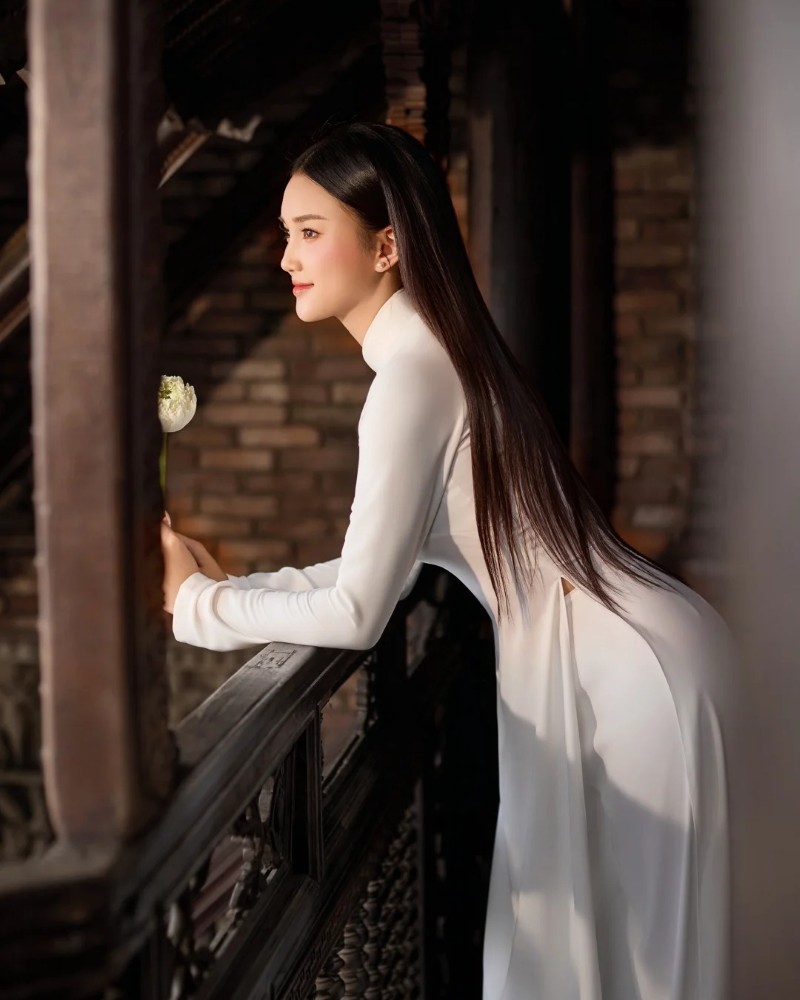 Cô gái mặc áo dài tạo dáng bên cửa gỗ