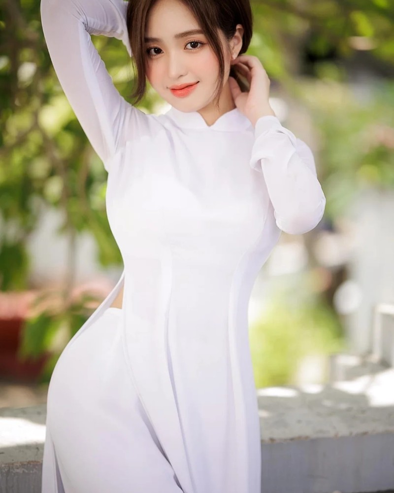 gái xinh mặc áo dài tạo dáng nhẹ nhàng ngoài trời