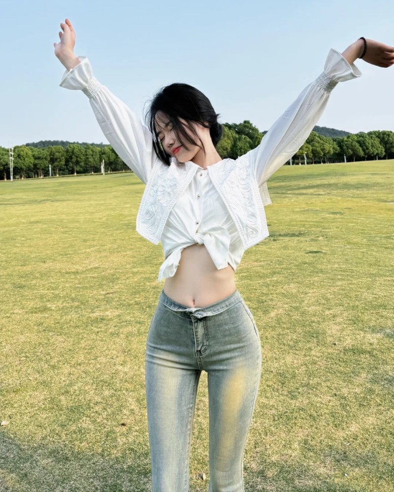 Nhân vật nữ mặc quần bó sát tạo dáng giữa bãi cỏ