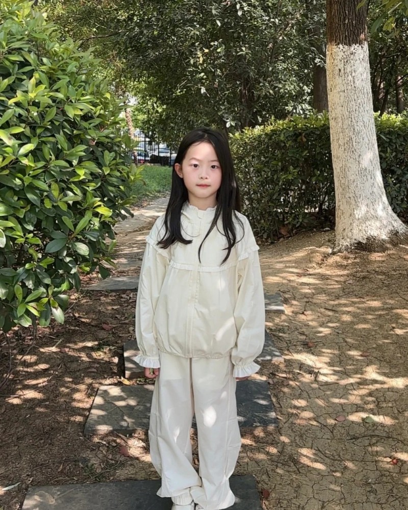 hình bé gái dễ thương mặc áo trắng tạo dáng ngoài vườn