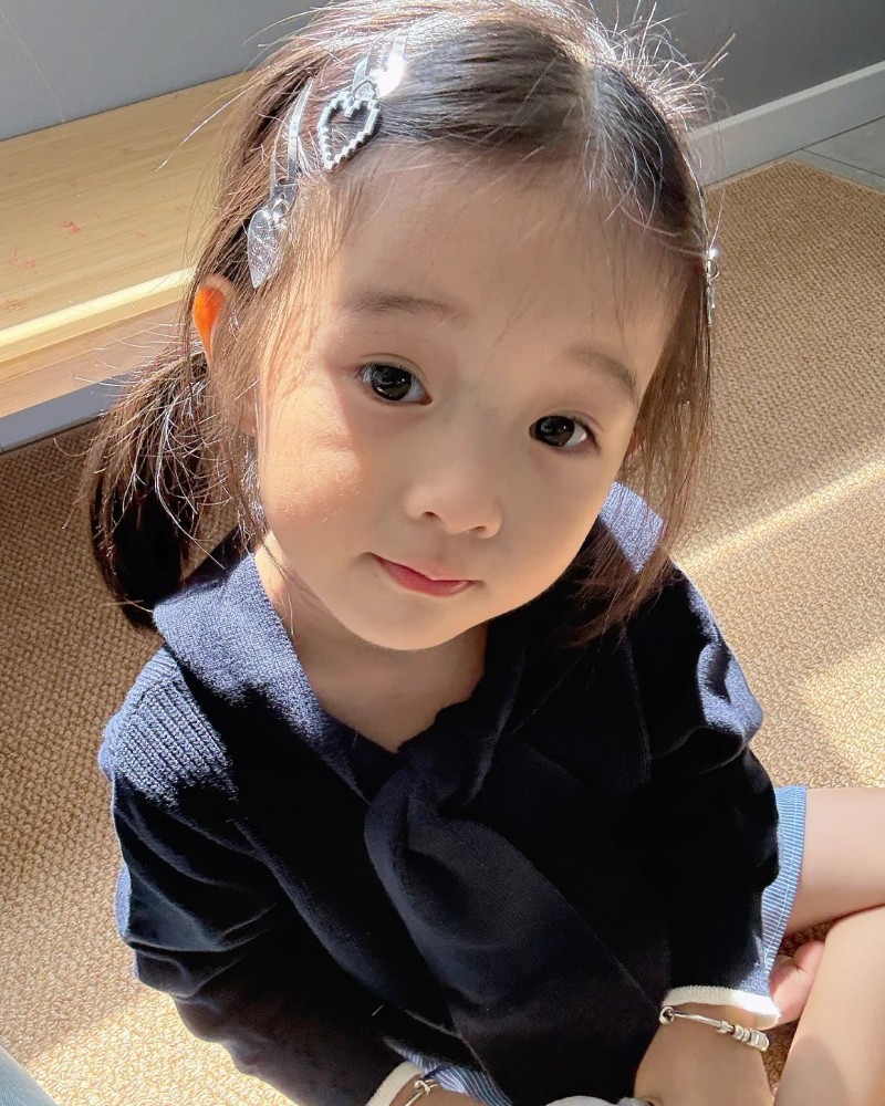 bé gái cười nhẹ trong bộ đồ mùa đông