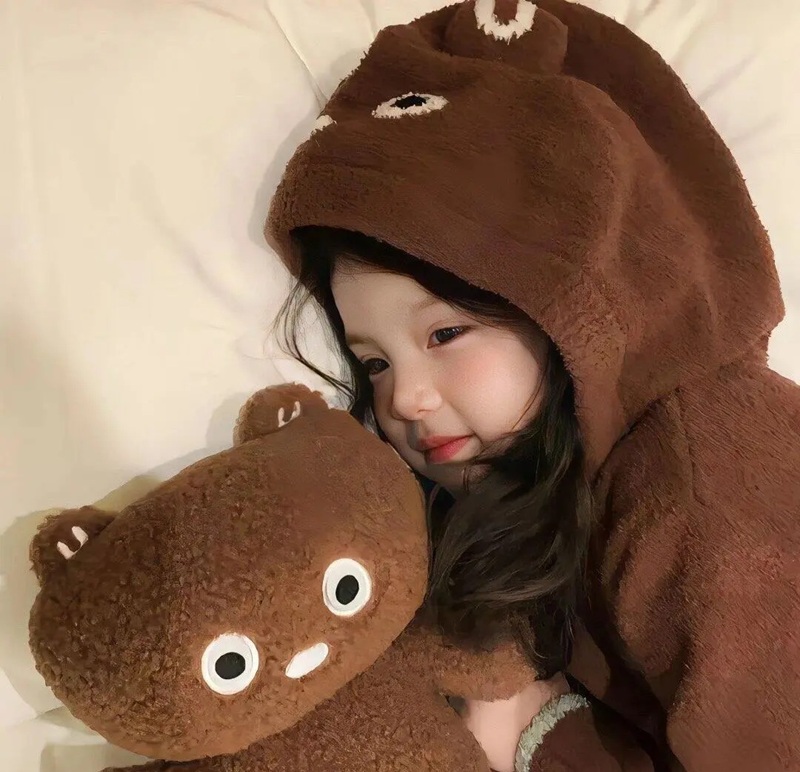 bé gái quấn khăn ấm chơi với thú bông