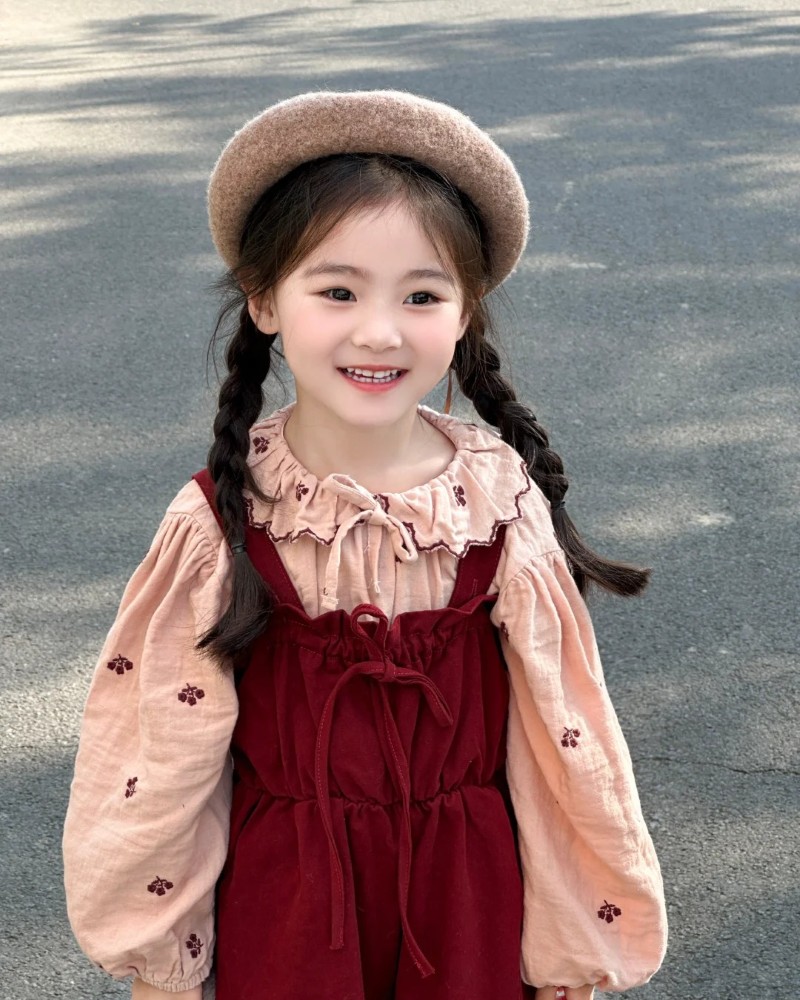 bé gái mặc váy đỏ pose trước cổng