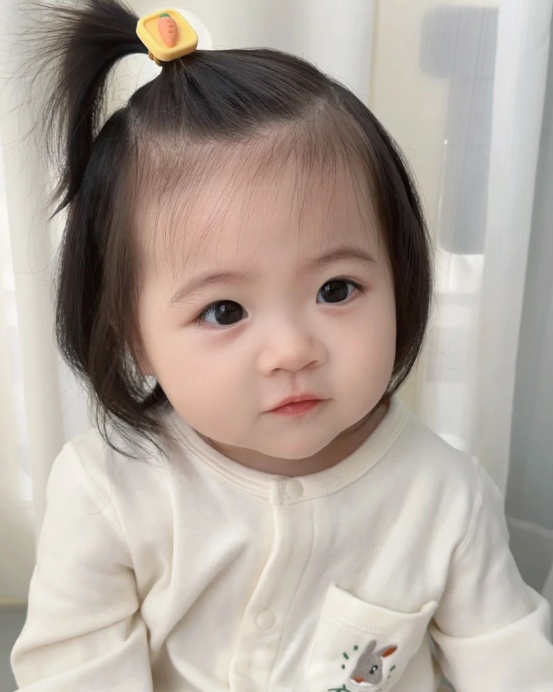 bé gái ngồi ghế nhìn ống kính đáng yêu