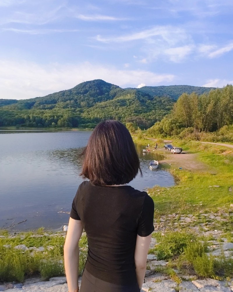 bạn nữ tóc ngắn đứng trước khung cảnh thiên nhiên