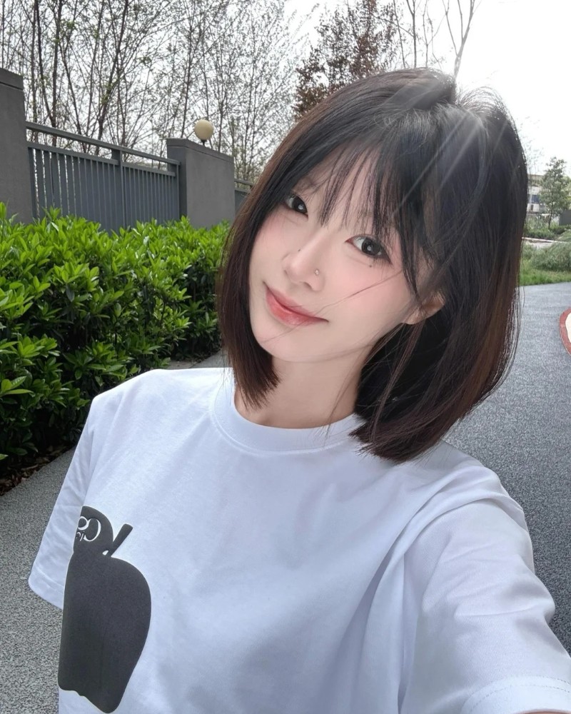 cô gái tóc ngắn cười nhẹ ngoài sân